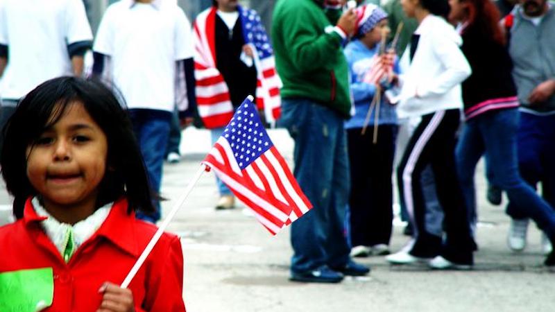 Young girl in red jacket holding an American flag. CREDIT: jvoves from Openverse