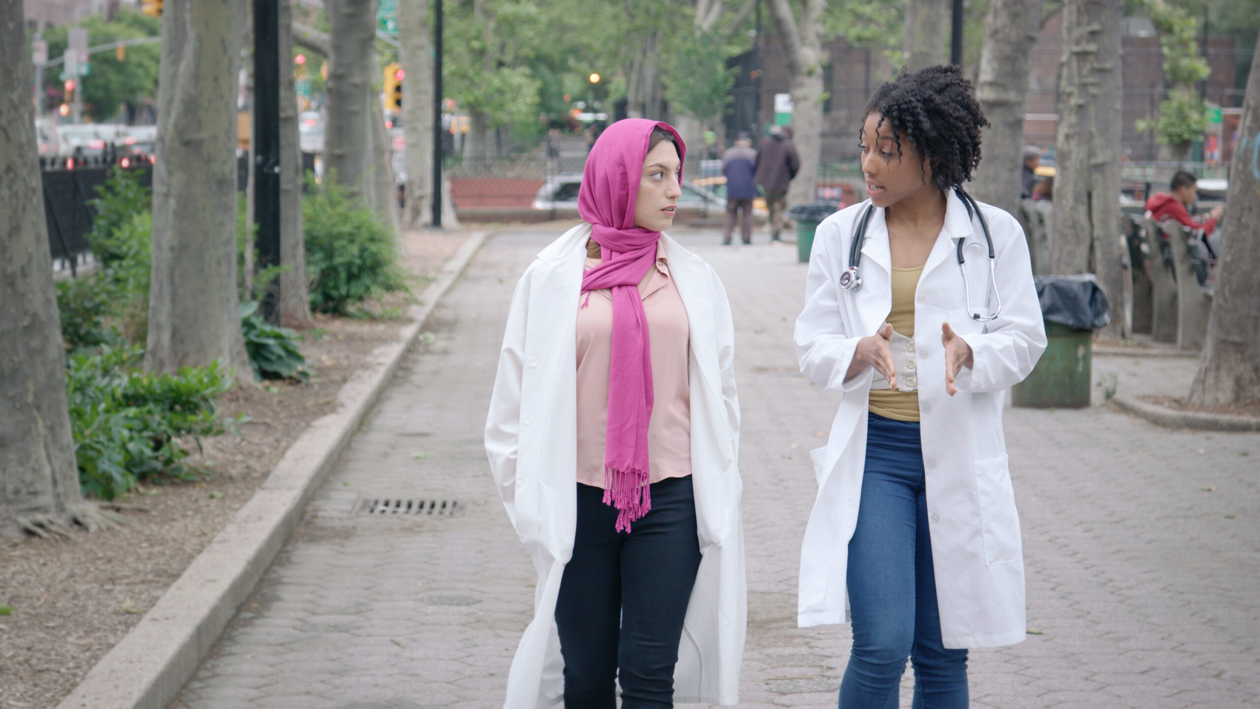 two people in medical coats having a discussion on the street